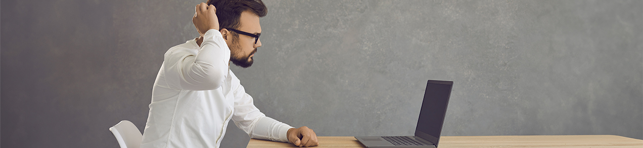 Staff member confused scratching head looking at laptop