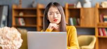 Woman sits at laptop in library scrutinizing whether an email is phishing or not