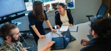 UBC staff attend a team meeting in a boardroom with laptops