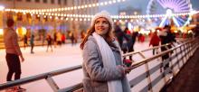 Smiling woman in winter style clothes with coffee near skating rink. 