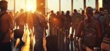 Busy airport scene with travelers silhouetted against a sunset