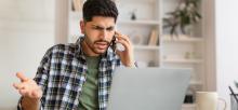 Man confused on phone looking at laptop